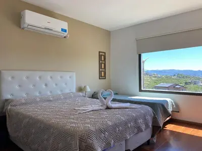 a bedroom with a bed with a large window at LA CASITA in Villa Carlos Paz