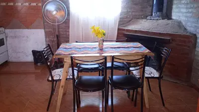 a dining room table with chairs and a fireplace at Chalet y Cabaña de montaña Esmeralda in Villa del Dique