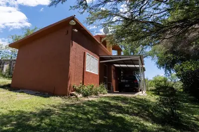 a red brick building with a car in the garage at Chalet y Cabaña de montaña Esmeralda in Villa del Dique