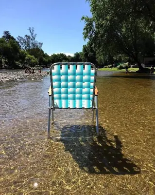 a chair sitting in the water in a body of water at Chalet y Cabaña de montaña Esmeralda in Villa del Dique