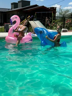 two girls in the water on inflatables in a swimming pool at Complejo de Cabañas Los 2 Soles 9 in Los Reartes