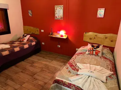 two beds in a room with red walls and a candle at Complejo de Cabañas Los 2 Soles 9 in Los Reartes