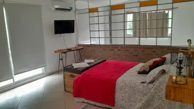 a bedroom with a bed with a red blanket at El Rinconcito de la Selva in La Calera