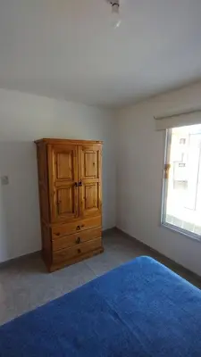 a bedroom with a wooden dresser and a blue rug at El Roble, casa de sierra in Estancia Vieja