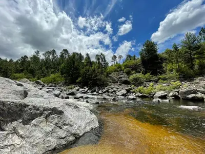 a river with rocks and trees in the background at Ayllupelli in Villa Berna