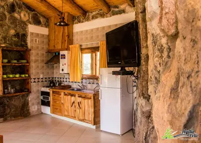 a kitchen with a refrigerator and a tv on a wall at Ayllupelli in Villa Berna