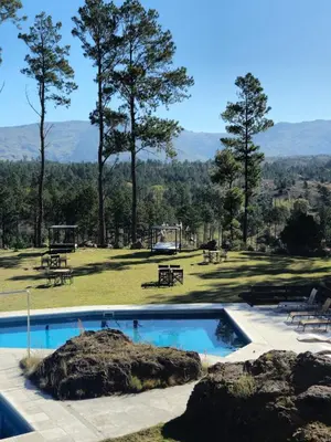 a swimming pool in a park with picnic tables and trees at Ayllupelli in Villa Berna