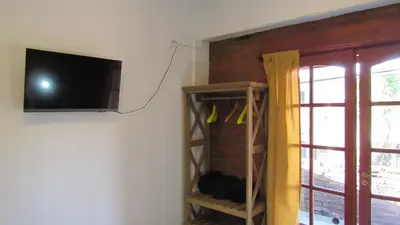 a tv hanging on a wall next to a shelf at Suites Del Centro in Santa Rosa de Calamuchita
