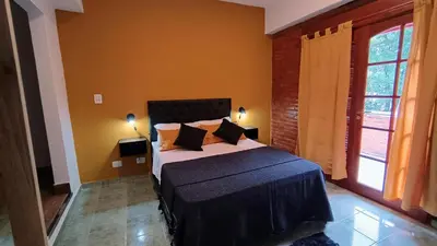 a bedroom with a large bed with two windows at Suites Del Centro in Santa Rosa de Calamuchita