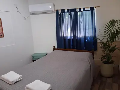 a bedroom with a bed with a blue curtain and a window at Don Carlos, para 2 personas con aire in Villa Cura Brochero