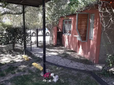 a red building with a window and flowers in the yard at Don Carlos, para 2 personas con aire in Villa Cura Brochero