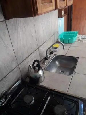 a kitchen sink with a tea kettle on the stove at Don Carlos, para 2 personas con aire in Villa Cura Brochero
