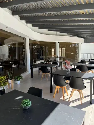 a restaurant with black tables and chairs and windows at Hotel Storge by CPH in Villa Carlos Paz