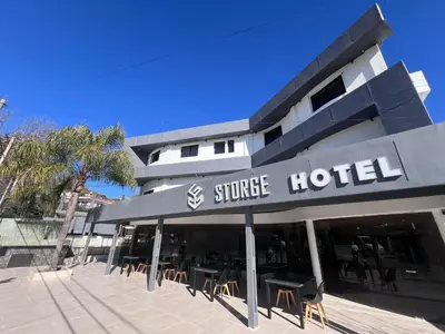 a hotel with tables and chairs in front of a building at Hotel Storge by CPH in Villa Carlos Paz