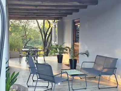 a porch with chairs and tables and a patio at Raíces serranas in Villa de Las Rosas