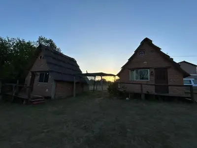two houses in a field with the sunset in the background at baja in Villa Carlos Paz