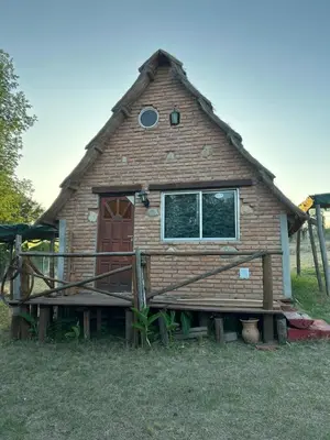 a house with a thatched roof with a porch at baja in Villa Carlos Paz