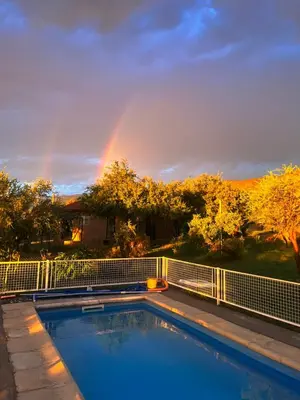 a pool with a rainbow in the background at Flor Silvestre in Carpintería