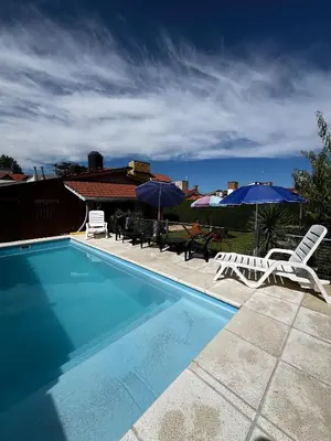 a swimming pool with two lawn chairs and umbrellas at La Merlina in Merlo