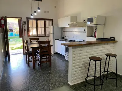 a kitchen with a table and some stools in it at La Merlina in Merlo