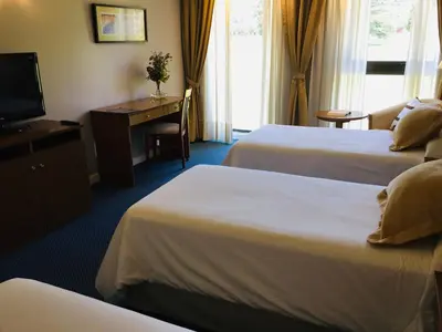 a hotel room with two beds and a desk and a television at San Miguel Plaza Hotel All Inclusive in Villa San Miguel