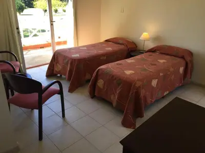 a room with two beds and a chair and a window at San Miguel Plaza Hotel All Inclusive in Villa San Miguel