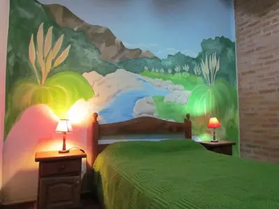 a bedroom with a bed with a painting on the wall at Cabañas de Montaña San Miguel in Cortaderas