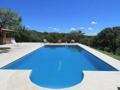 a large swimming pool with blue water in a yard at Cabañas de Montaña San Miguel in Cortaderas