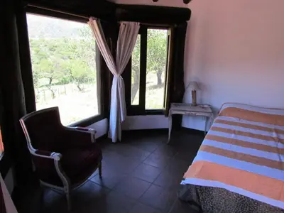 a bedroom with a bed and a chair and a window at Cabañas de Montaña San Miguel in Cortaderas