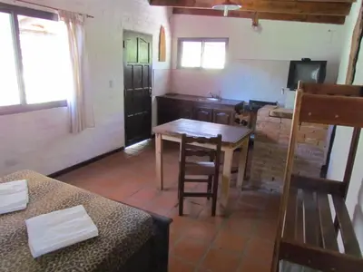 a small room with a table and a kitchen at Cabañas de Montaña San Miguel in Cortaderas