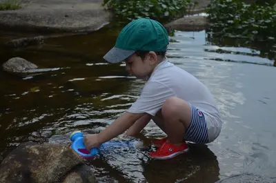 a young boy playing with his shoes in the water at Hosteria Sans Souci in Tanti
