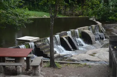 a waterfall in a park with a bench next to a pond at Hosteria Sans Souci in Tanti