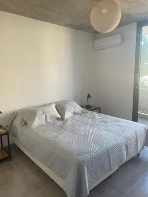a bed in a bedroom with a white wall at DEPARTAMENTO Guemes a mts de Nva Córdoba y centro Terraza y pileta! in Cordoba