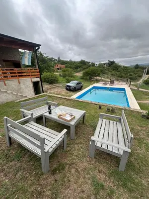 two picnic tables and a swimming pool with a car at Estancia Charo in Villa Carlos Paz