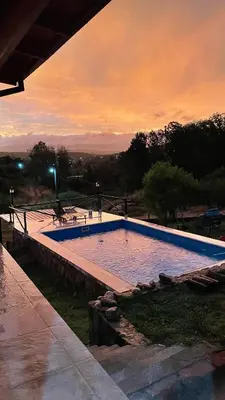 a large swimming pool with a sunset in the background at Estancia Charo in Villa Carlos Paz