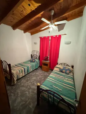 two beds in a room with red curtains at Estancia Charo in Villa Carlos Paz