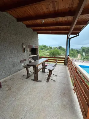 a wooden patio with a table and benches on a deck at Estancia Charo in Villa Carlos Paz