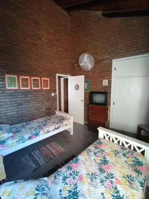 a bedroom with two beds and a brick wall at Gracias Viejo in Merlo