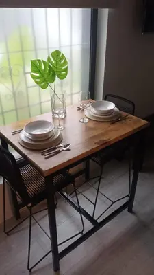 a wooden table with plates and glasses and a plant at Departamento Zona Norte, Kempes, Allende Cerro in Cordoba