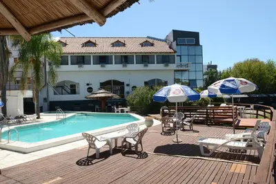 a pool with chairs and umbrellas next to a building at Hotel El Condado in Villa Carlos Paz