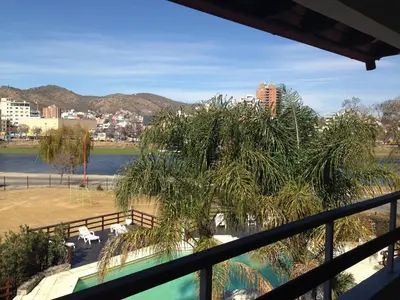 a balcony with a tree and a view of a lake at Hotel El Condado in Villa Carlos Paz