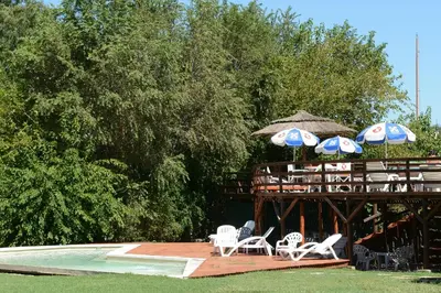 a deck with chairs and umbrellas next to a pool at Hotel El Condado in Villa Carlos Paz