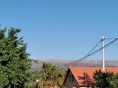 a house with a red roof with mountains in the background at La Mora Casa in Mina Clavero