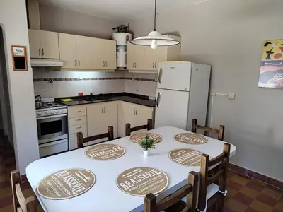 a kitchen with a white table and a refrigerator at La Mora Casa in Mina Clavero