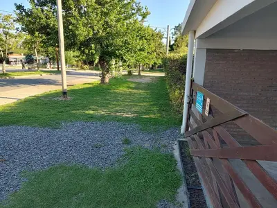 a wooden fence next to a house with grass at La Mora Departamento in Mina Clavero