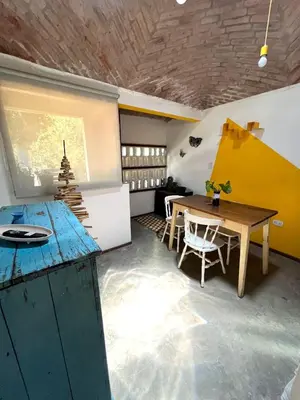 a room with a wooden table and a yellow wall at CASITA PINTORESCA EN LAS SIERRAS Y LAGO in San Roque