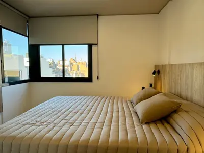 a bedroom with a large bed with a large window at Rent a Flat Nueva Cordoba in Cordoba