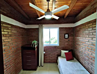 a ceiling fan in a room with a brick wall at Departamento Olmos in Mina Clavero