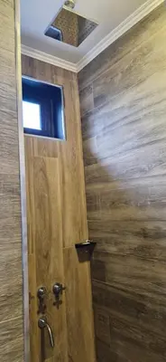 a bathroom with a wooden door with a television on the ceiling at Vivisierras, Piso 4 frente al lago Centro Villa Carlos Paz, pileta privada, vista panorámica in Villa Carlos Paz