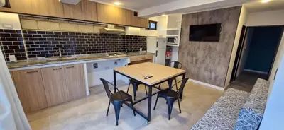 a kitchen with a table and chairs in a room at Vivisierras, Piso 3 frente al lago, centro Villa Carlos Paz, 2 dormitorios, 2 baños, pileta privada, premium in Villa Carlos Paz